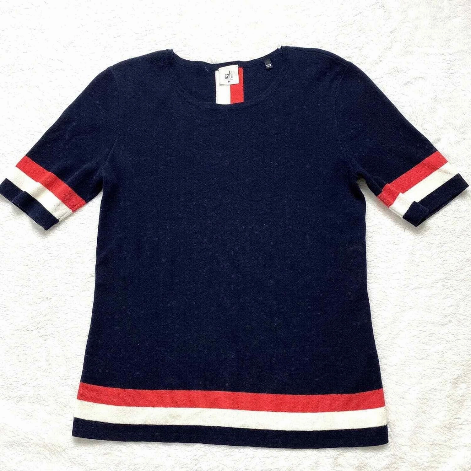 Cabi Hampton Shell Knit Top, is Navy with red and White Stripe at Sleeve and Hem.