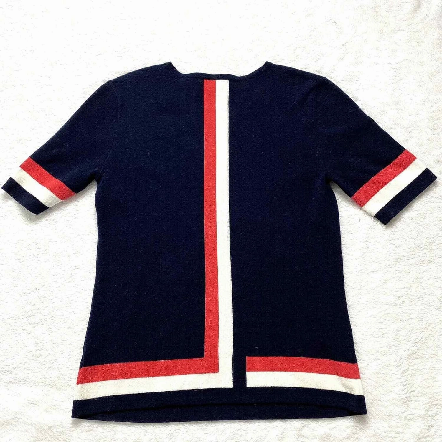 Cabi Hampton Shell Knit Top, is Navy with red and White Stripe at Sleeve and Hem.